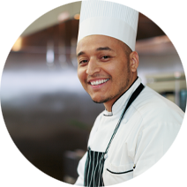 Young man wearing a chef's hat with a short beard and an apron