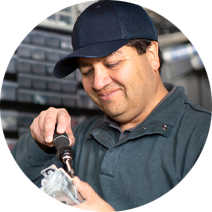 Maintenance man wearing a dark cap and using a screwdriver to fix something